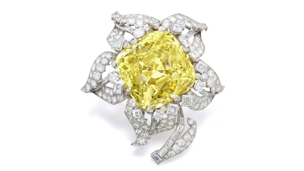 Cartier Allnatt diamond brooch containing a round-cornered square brilliant-cut fancy-vivid-yellow diamond, with diamond petals and leaves at Sotheby’s image