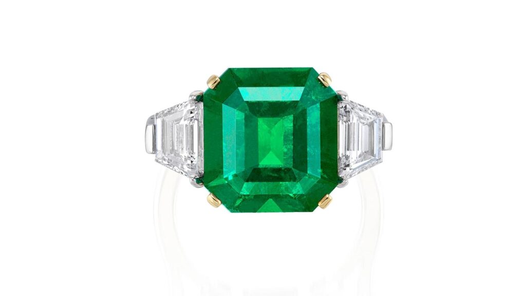 Ring featuring a step-cut Colombian emerald between two trapezoid step-cut diamonds at Phillips image