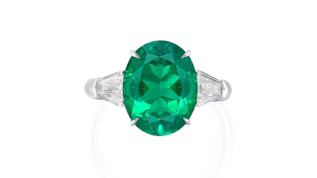 Ring, set with an oval-shaped Colombian emerald flanked by two calf’s-head shaped diamonds at Phillips image