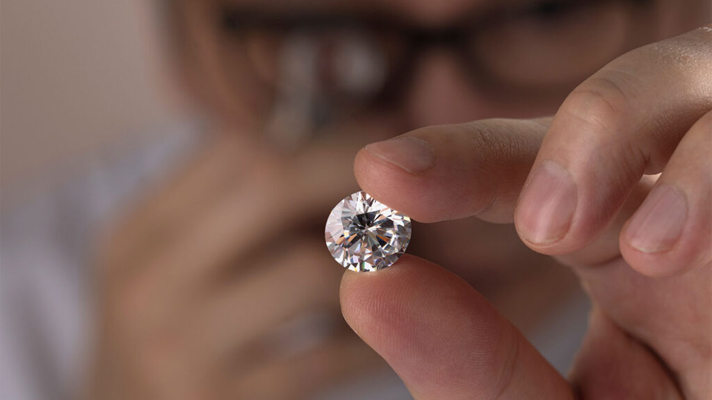 Man inspecting polished diamond with a loupe image