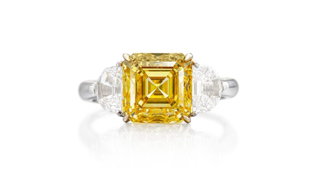 Ring, bearing a step-cut, fancy-vivid-yellow, diamond between two epaulette-shaped diamonds at Sotheby's image